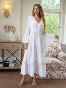 Dettaglio ravvicinato di un abito bianco stile boho con scollo a V, maniche a fessura e pizzo