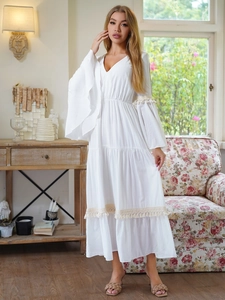 Dettaglio dell'abito lungo boho bianco con scollo a V, maniche a campana e nappe decorative