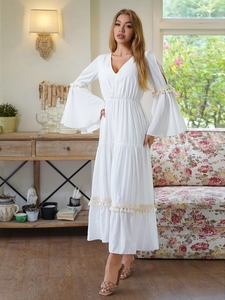 Dettaglio dell'abito boho bianco con scollo a V, maniche a campana e nappe in pizzo