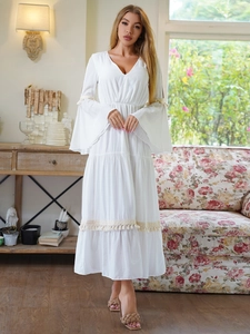 Dettaglio dell'abito boho bianco con scollo a V, maniche a campana ed eleganti bordi con nappe