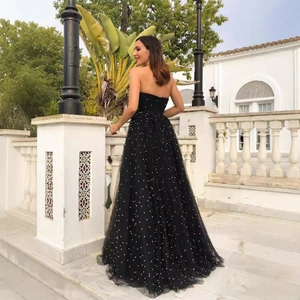 Elegant floor-length black strapless evening gown with colorful sequins in a garden setting