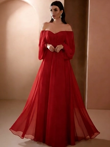 Detail of red off-shoulder evening gown featuring lantern sleeves and elegant V-neckline