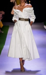 Runway detail of a white off-shoulder maxi dress with a wide green leather waist belt