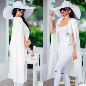 Vue détaillée d'une cape blanche pour femme avec chapeau fedora assorti et jean déchiré chic