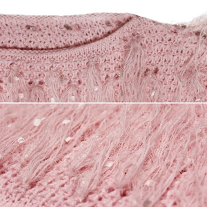 Détail d'un pull en tricot rose avec des franges faites à la main et des paillettes