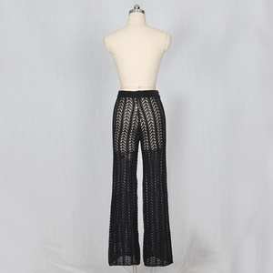 Détail du pantalon large en tricot noir avec motifs géométriques ajourés et taille côtelée