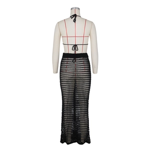 Detail of black crochet knit beach set featuring halter top and openwork long skirt