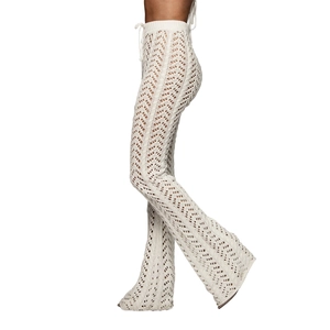 Détail du pantalon évasé en crochet blanc montrant la texture ajourée et le cordon