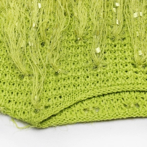 Détail de tricot vert avec maille épaisse, fils de cils et paillettes discrètes