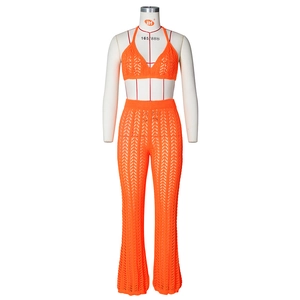 Detail of bright orange crochet knit halter bikini top and matching hollow trousers
