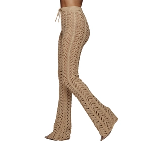 Détail du pantalon en maille crochet beige avec texture ondulée et coupe évasée