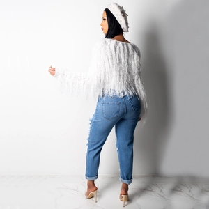 Rear view of white fringe knit sweater with textured tassels and distressed blue jeans