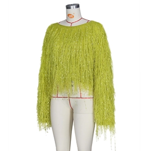 Détail d'un pull en maille vert herbe avec des franges denses et des paillettes brillantes