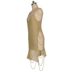 Détail de la découpe latérale sur robe dorée en maille métallique avec chaînes
