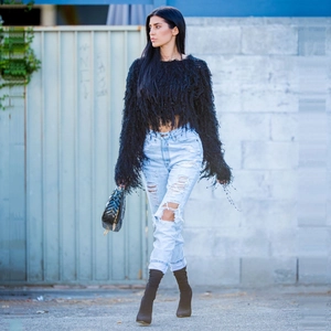 Close-up of black fringe knit top paired with distressed light blue jeans in street style