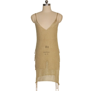 Détail de robe en maille dorée champagne avec col en V et ourlet à glands en chaîne métal