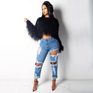 Close-up of black fringed knit sweater with long tassels and distressed blue denim jeans
