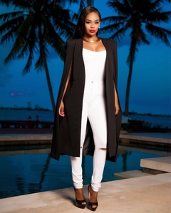 Veste de costume longue cape noire avec jean blanc déchiré et talons hauts en soirée