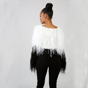 Back view of black and white color-block sweater featuring handmade fringe tassels