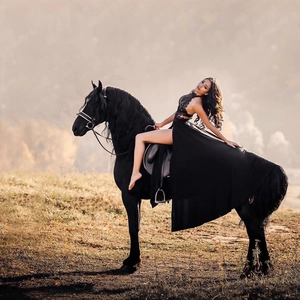 Elegant black lace evening dress with high slit shown on horseback in nature scenery