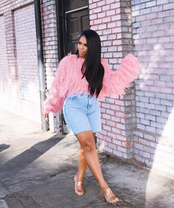 Détail du pull rose à franges et du short en jean taille haute porté par un mannequin