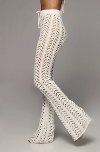 Détail du pantalon évasé en tricot blanc avec motif ajouré et cordon de serrage