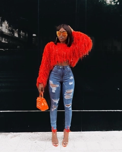 Détail d'un pull en maille plume rouge et d'un jean en denim vieilli à taille haute moderne