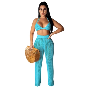 Detail of bright blue crochet halter top and hollow-out pants with woven bag