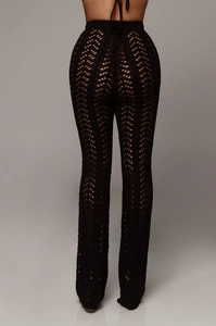 Détail du pantalon en maille crochet noire avec motifs ajourés ondulés et texture transparente
