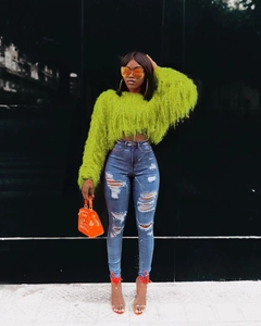 Vue détaillée du pull tricoté vert vif à franges pour femmes et jean bleu déchiré
