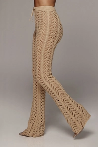 Détail du pantalon évasé en maille crochet kaki avec des motifs de vagues ajourés