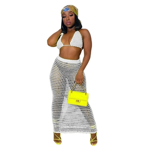 Detail of white crochet knit beach set featuring halter bikini top and hollow mesh maxi skirt