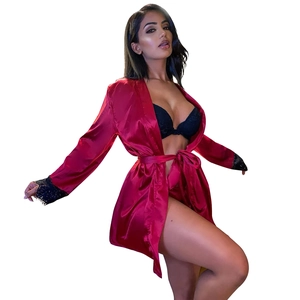 Close-up of red satin robe sleeves featuring delicate black lace trim and silk texture