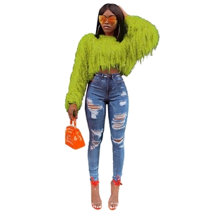 Détails du pull à franges vert vif et du jean skinny bleu avec des déchirures usées