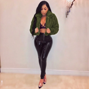 Detail of a short dark green faux fur jacket with thick lapels and glossy leather pants