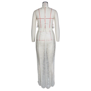 Detail of white crochet knit two-piece set with halter top and tassel skirt texture