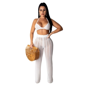 Detail of white crochet two-piece set featuring knit halter top and flare pants