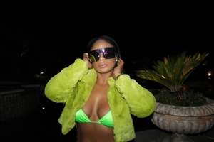 Short faux fur jacket in neon green paired with matching bikini top and dark sunglasses