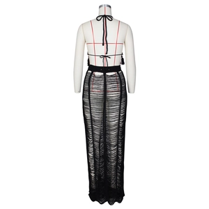 Detail of black knit two-piece beach set with backless halter top and hollow out maxi skirt