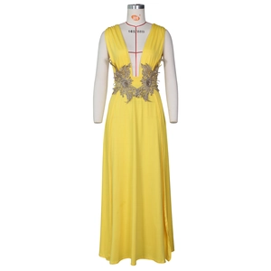 Détail de la broderie de feuilles dorées et du décolleté en V de la robe jaune de soirée