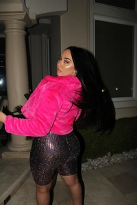Close-up of bright pink faux fur hooded jacket with black rhinestone shorts for clubwear
