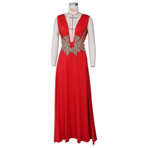 Détail de la robe de soirée rouge avec décolleté en V et broderies de dentelle dorée