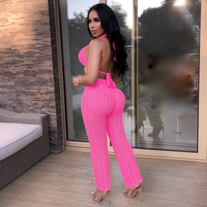 Detail of neon pink crochet knit two-piece set featuring halter top and hollow out trousers