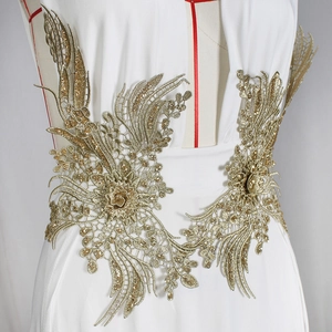 Détail de broderie en dentelle à paillettes dorées sur une robe de soirée fendue
