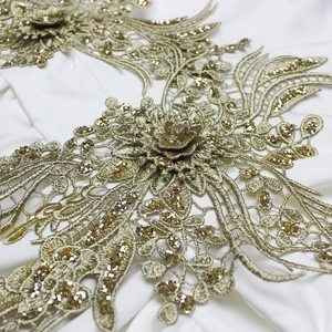 Gros plan sur la dentelle brodée de fleurs 3D dorées et paillettes pour robes de soirée