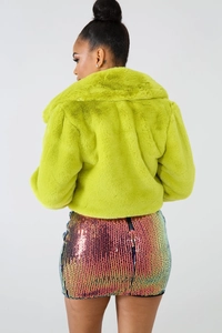 Back view of a neon green faux fur cropped jacket paired with a colorful sequin skirt
