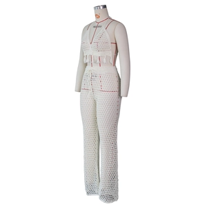 Detail of white crochet knit two-piece set featuring halter top with fringe and mesh pants