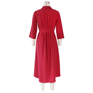 Detail view of the back of a deep red long-sleeved dress with waist belt and pleated hem