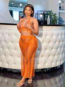 Detail of bright orange two-piece knit set featuring fringe tassel trim and crochet hollow out