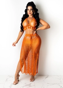 Detail of orange crochet two-piece set featuring tassel halter top and side slit maxi skirt